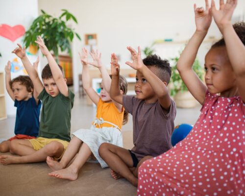 Group of small nursery school children sitting on floor indoors in classroom, playing. A group of small nursery school children sitting on floor indoors in classroom, playing.